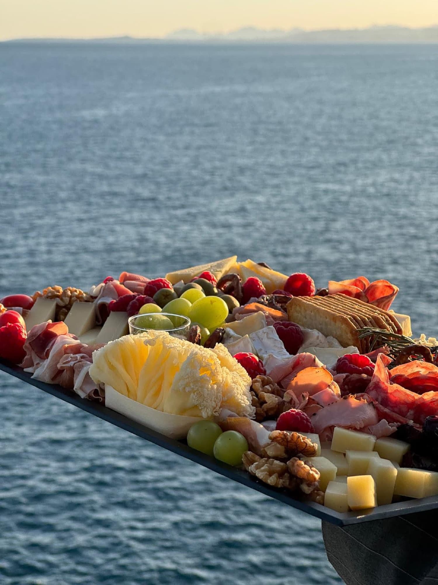 Plateau de charcuterie et fromages dressé face à la mer au coucher du soleil, catering à bord ALL YACHT