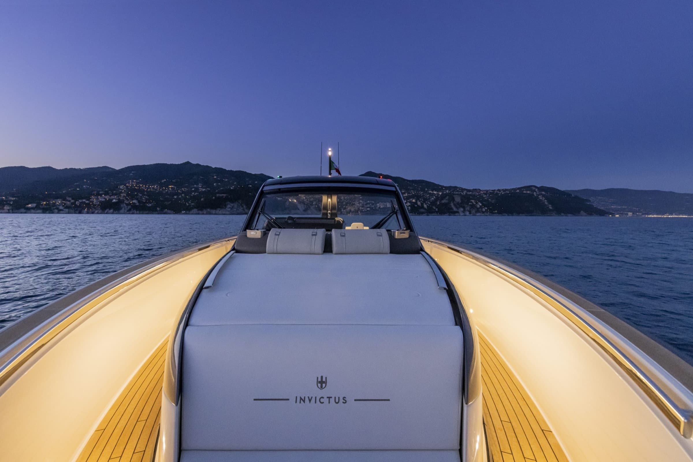 La plage avant de l'Invictus TT 460 au crépuscule devant la côte de la Riviera