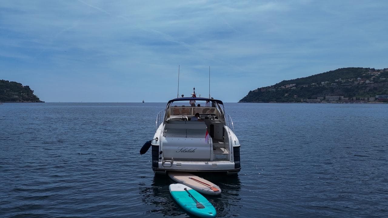 La poupe du Princess V42 au mouillage, paddles à l'eau devant le littoral de la Riviera