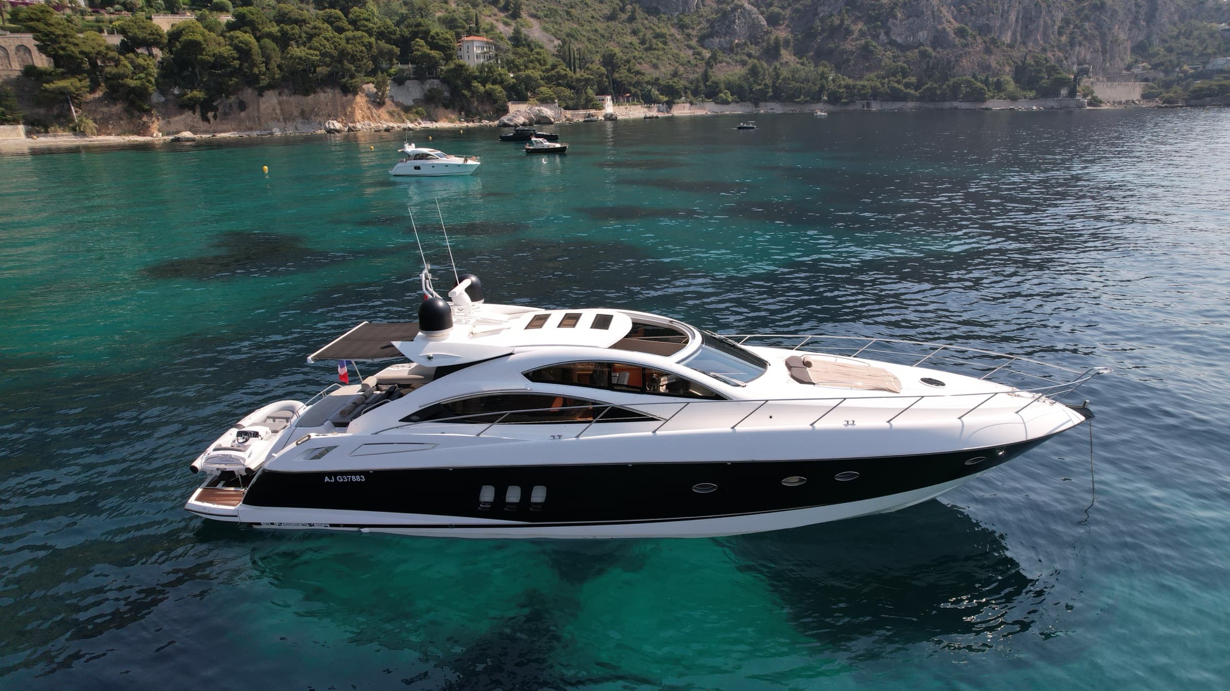 Profil du Sunseeker Predator 62 au mouillage devant la côte rocheuse de la Riviera